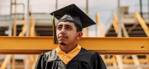 Graduate standing in front of scaffolding on a work site.